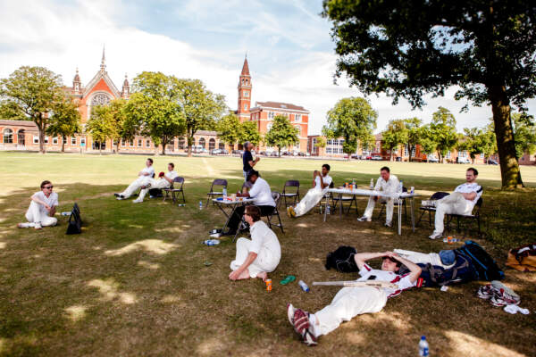 Team members relaxing on the Dulwich College playing fields after a corporate cricket match.